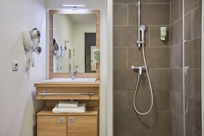 The well-appointed bathroom features a modern design with wooden cabinetry, a large mirror, and a spacious shower area.