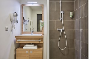 The well-appointed bathroom features a modern design with wooden cabinetry, a large mirror, and a spacious shower area.