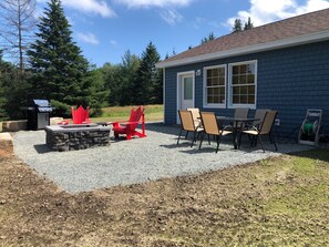 Patio off back of house with grill, fire pit and table with chairs