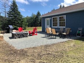 Patio off back of house with grill, fire pit and table with chairs