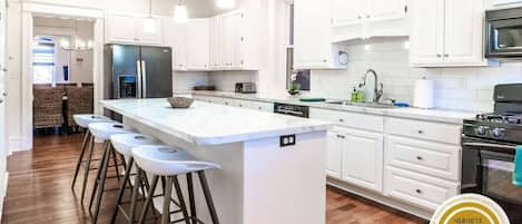 The custom, fully equipped chef’s kitchen with a marble top breakfast bar