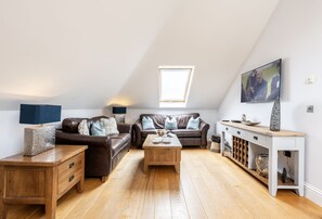 9 Fernhill Penthouse, Carbis Bay. Open-plan sitting room with two leather sofas, coffee table and smart television