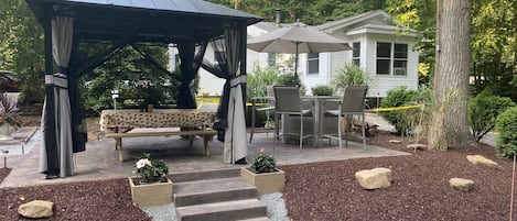 Paved patio with gazebo, picnic table, and bar set