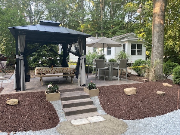 Paved patio with gazebo, picnic table, and bar set