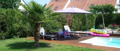 Terrasse détente piscine avec bain de soleil et parasol 