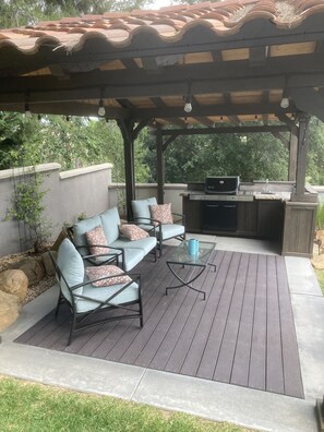 Covered seating area barbecue, sink, refrigerator.