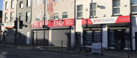 Frontage to property entrance grey door between FSC property and The Kop End Bar