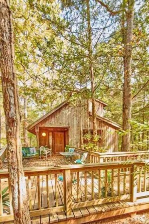 Cabin front porch & deck are surrounded on 3 sides by woods, a creek bed & peaceful outside places to commune with nature amid majestic pines, oaks, dogwood & redbud trees & American beauty bushes.