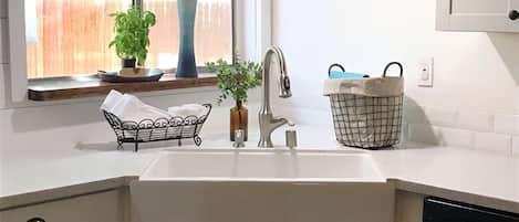 Large Farmhouse sink with a backyard view 