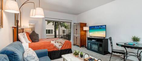 Cozy studio with queen bed, sofa bed, and outdoor patio view.