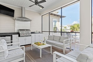 Screened-in porch with built-in grill and comfortable seating.