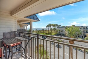 Perfect Perch – The covered balcony is a wonderful place to hang out, offering a glimpse of the beach and ocean, waving palms, and endless blue skies.
