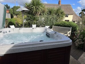 Large heated hot tub in the garden of Rose Cottage with decking and seating