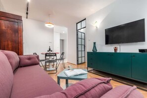 Stylish living room with a sofa bed, TV, dining area and closet.