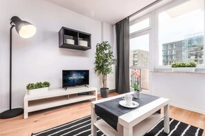 Living room with a sofa bed, TV and access to the balcony.