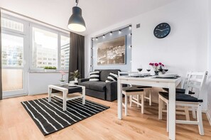 Living room with a sofa bed, TV, dining area and access to the balcony.