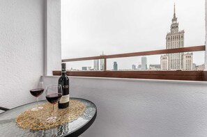 A cozy outdoor terrace featuring a small round table with two glasses of wine, offering a panoramic view of the city, making it an ideal space for relaxing.