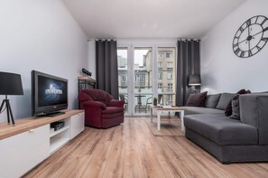Living room with a sofa bed, TV and access to the balcony.