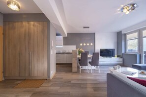 An open-plan view showing the kitchen flowing into the dining and living areas, emphasizing the airy layout and warm lighting.