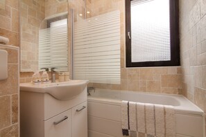 Bathroom with a tub and overhead shower