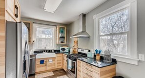 Enjoy a fully equipped kitchen, remodeled with new hardwoods, custom cabinets, sleek countertops, a gas stove, and a cozy dining space. 