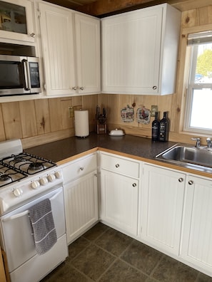 Adorable kitchen with a gas stove and refrigerator/freezer.