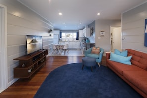 Living room has comfy seating, a flat screen tv and opens to the kitchen