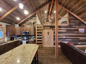 kitchen, living, barn door to bedrooms, bathroom, and laundry. Ladder to loft.