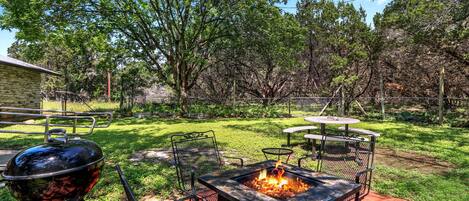 Private back yard with fire pit, charcoal grill, and dining table.