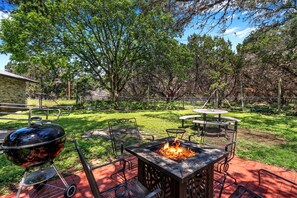 Private back yard with fire pit, charcoal grill, and dining table.