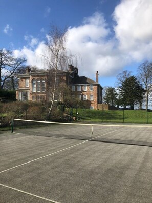 The hard tennis court with the back of the Hall and Wing