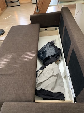 Two twin air mattresses and a pump are stored in the brown sofa sleeper