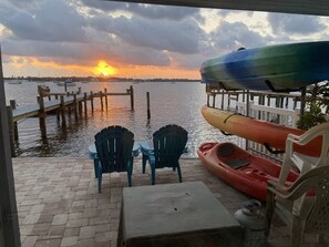 Sunrise with kayaks, fire pit, and chairs on paver patio next to Sarasota Bay