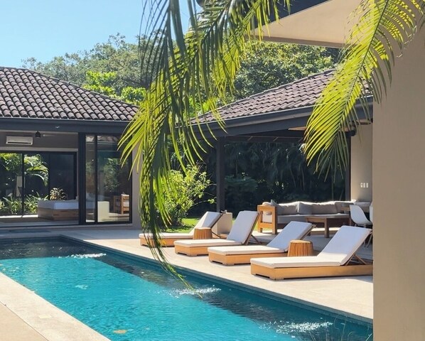 Resort style pool surrounded by lush vegetation, bedrooms & outdoor lounge area 
