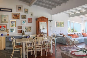 Lounge/dinning area with table for 8 and a modern big sofa in the front area.