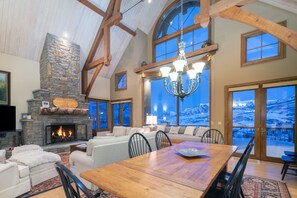 A fireplace is lit in the living area, next to the dining area with seating for 6.