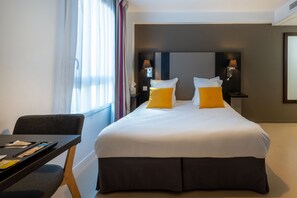 The clean lines of the modern furniture harmonize with pops of color, as the inviting bed arrangement and functional dining area enhance the studio's welcoming and stylish feel.