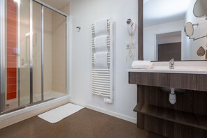 The stylish bathroom boasts a modern glass shower and elegant vanity, featuring ample storage and contemporary fixtures.