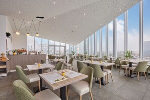 Elevated breakfast area with city views—floor-to-ceiling windows create an airy, light-filled setting.