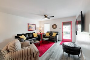 Large comfortable furnishings, excellent modern décor and TV. This view shows the door to the balcony and abundance of natural light.