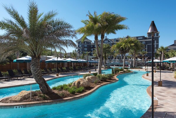  Winding resort pool with tropical landscaping, perfect for leisurely swims.
