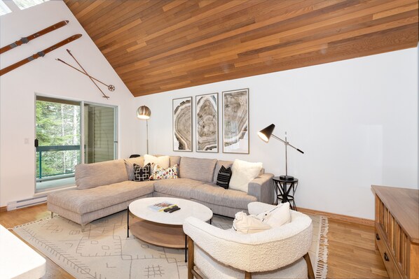 Living area is well-lit with oversized windows and vaulted ceilings
