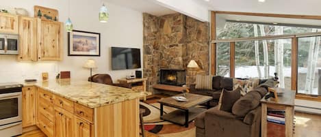 The open concept living area features a flat screen TV, wood burning fireplace and a warm and inviting atmosphere.