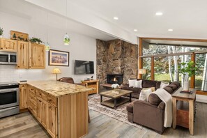 The open concept living area features a flat screen TV, wood burning fireplace and a warm and inviting atmosphere.