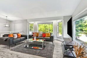 Open-concept living area with vibrant accents, large windows with tree views