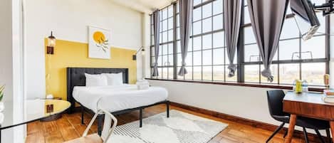 Queen-size bed with huge windows overlooking the city