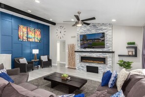 Huge family room with wrap around sectional, falt screen TV, fireplace, and ceiling fan