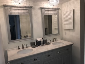 Master bath with double sinks and bright lighting.