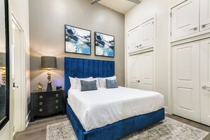 Spacious master bedroom with king bed, ensuite bathroom, and designer built-in closets. Equipped with a nightstand, lamp, hangers, luggage racks, alarm clock, white noise machine, and 50'' Samsung Smart 4K TV with streaming and DIRECTV Entertainment.
