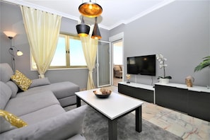 Modern lounge with confortable seating, international TV and balcony access